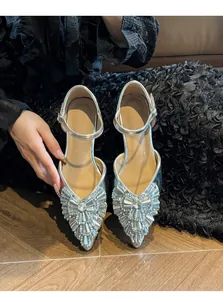 Detail shot of elegant silver rhinestone low-heel sandals with an ankle strap buckle