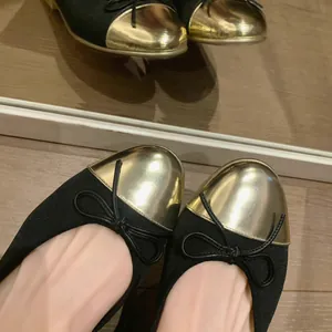 Vista detallada de elegantes bailarinas negras con punta de metal dorado y detalle de lazo