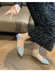 Detailed view of silver pointed toe flats with sparkly rhinestone bow decoration.