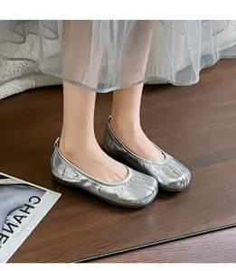 Ballerine metallizzate argento con punta divisa e dettagli increspati su parquet