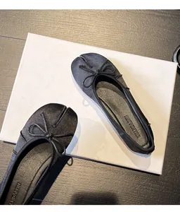 Detailed view of elegant black split-toe ballet flats with decorative bow tie.