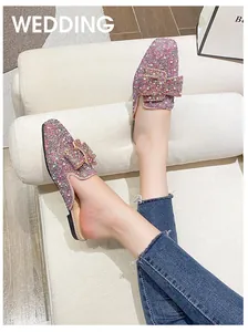 Detailed view of pink glitter flat mules featuring a sparkling rhinestone buckle on feet