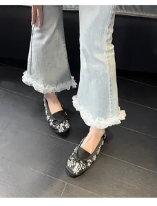 Vue détaillée de ballerines noires avec strass fleuris et nœud sur un jean bleu