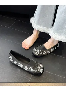 Vue détaillée de ballerines en satin noir ornées de fleurs en cristal et d'un nœud