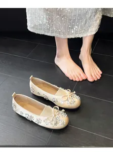 Gros plan sur des ballerines champagne avec fleurs en strass et nœud papillon