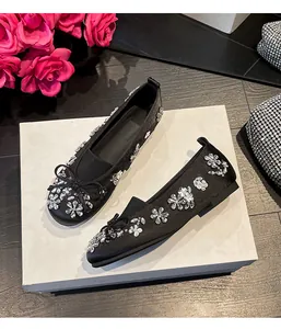 Gros plan de ballerines noires avec des motifs de fleurs en strass et un nœud délicat.