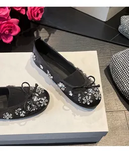 Gros plan de ballerines noires avec des motifs floraux en strass et un nœud élégant.
