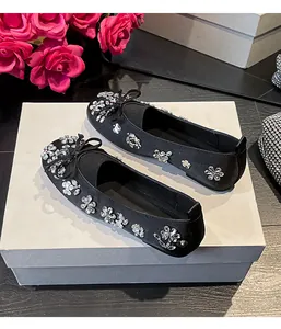 Ballerines noires élégantes avec bout rond, nœud et strass floraux étincelants.