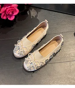 Détail de ballerines à bout rond avec nœud et décorations florales en strass étincelantes