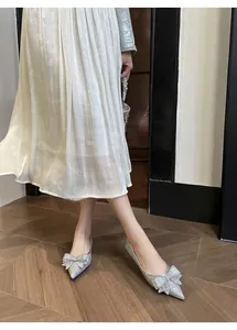 Dettaglio di ballerine argento a punta con fiocchi scintillanti e strass eleganti.