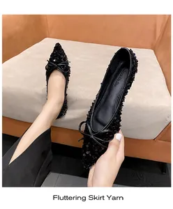 Detailansicht schwarzer Pailletten-Flachschuhe mit spitzer Zehenpartie und Schleife