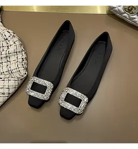 Nahaufnahme eleganter schwarzer Satin-Ballerinas mit funkelnder Strass-Schnalle