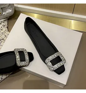 Detail der funkelnden Strass-Quadratschnalle auf eleganten schwarzen Satin-Ballerinas.