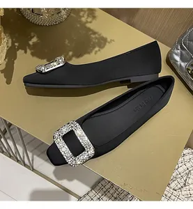 Nahaufnahme von schwarzen Seidensatin-Ballerinas mit luxuriöser Strass-Quadratschnalle