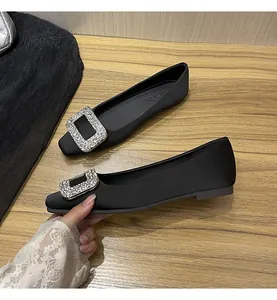 Detailansicht von schwarzen Satin-Ballerinas mit eleganter, quadratischer Strass-Schnalle.