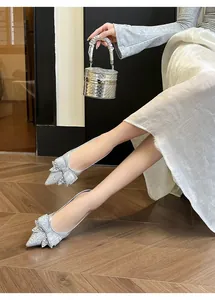 Dettaglio di ballerine a punta argento con fiocco decorato da strass luccicanti.