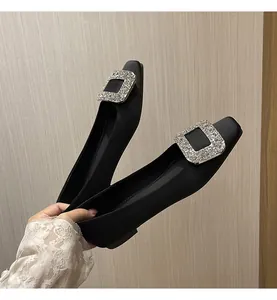 Detailansicht eleganter schwarzer Satin-Ballerinas mit einer großen quadratischen Schnalle