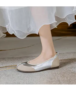 Nahaufnahme von eleganten Ballerinas mit Tabi-Zehen in Silber und Beige zum weißen Kleid