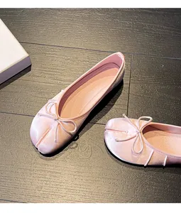 Close-up view of pink satin Tabi ballet flats with a delicate bow detail on wood floor