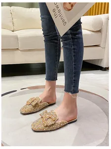Close-up of glittering rhinestone bow mules worn with casual jeans for daily style.