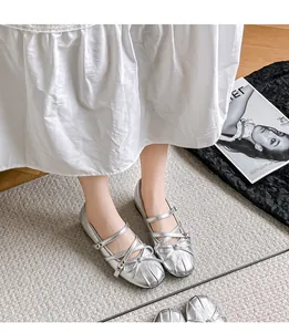 Nahaufnahme von silbernen Mary Jane Ballerinas im französischen Stil mit Schleife an den Füßen