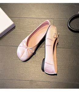 Close-up detail showing the split-toe design and delicate bow on pink satin ballet flats
