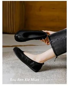Nahaufnahme von schwarzen Tabi-Flachschuhen, die Leder- und Wildlederstruktur zeigen