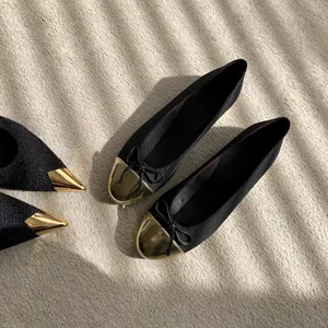Primer plano de elegantes bailarinas negras con puntera dorada y detalle de lazo