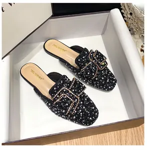 Macro view of black pointed toe mules with sparkling rhinestones and pearl details