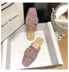Detailed shot of pink sparkly rhinestone flat mules presented in a premium gift box