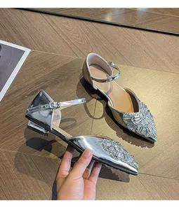 Detail of silver pointed-toe sandals with rhinestone embellishments and ankle strap.