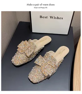 Detailed view of rhinestone and pearl embellished flat pointed-toe mules on display.