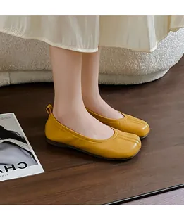 Primo piano di eleganti ballerine a punta divisa gialle plissettate su parquet scuro