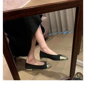 Primer plano de una modelo con bailarinas bicolor en negro y oro con detalle de lazo
