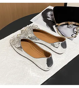 Detailed macro view of elegant silver ballet flats with rhinestone bow and pearl details.