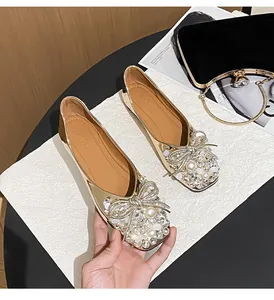 Close-up of gold fairy style flat shoes with rhinestone pearl bow decoration
