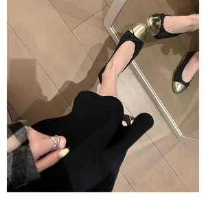 Primer plano de elegantes bailarinas bicolores en negro y dorado con detalle de lazo delicado