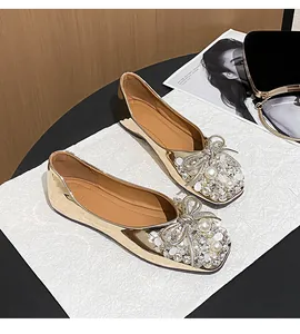 Detail of elegant gold wedding flats with sparkling rhinestone and pearl bow decor.