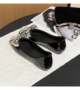 Detail view of elegant black patent leather flat shoes featuring exquisite rhinestone bow
