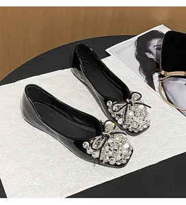Elegant black patent leather flats with rhinestone and pearl bow decoration