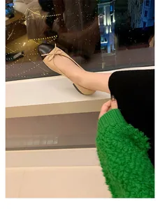 Primer plano de elegantes bailarinas bicolor en beige y negro con detalle de lazo delicado
