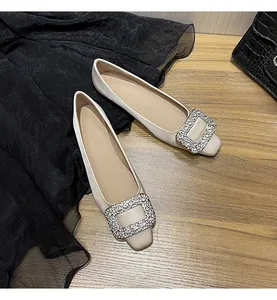 Detailansicht eleganter champagnerfarbener Satinschuhe mit glitzernden Strass-Schnallen.