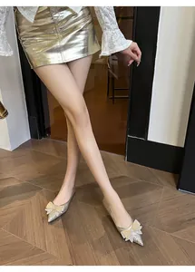 Dettaglio di ballerine glitterate a punta con fiocco di strass indossate