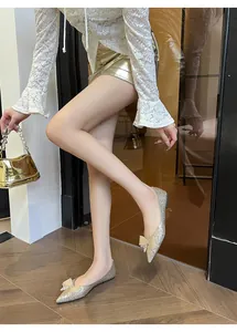 Modella indossa ballerine a punta glitterate con fiocco in un ambiente moderno.