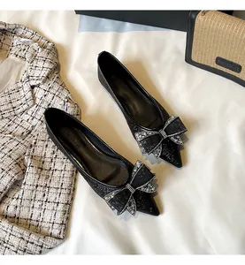 Dettaglio di eleganti ballerine nere a punta con un fiocco in strass luccicanti.