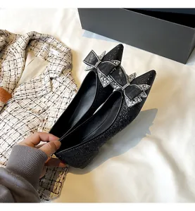 Dettaglio di eleganti ballerine nere a punta con fiocco in strass e finitura glitterata