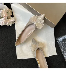 Elegante primo piano di ballerine glitterate a punta con un grande fiocco di strass.