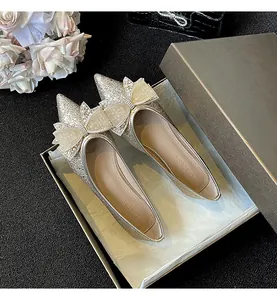 Dettaglio delle eleganti ballerine a punta con fiocco in strass in una scatola di lusso