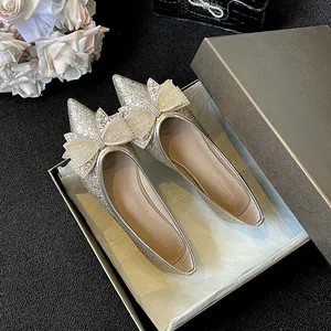 Eleganti ballerine dorate a punta con un fiocco di strass e perle in una scatola