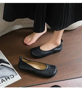 Vista dettagliata delle ballerine retrò nere con punta divisa per donna su legno